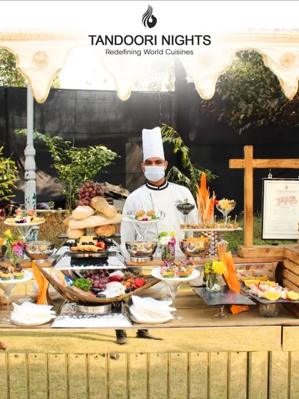 Our impeccably arranged tables are where elegance meets flavor. Here, a chef stands proudly behind a beautiful outdoor grazing table, ready to delight every guest's senses.