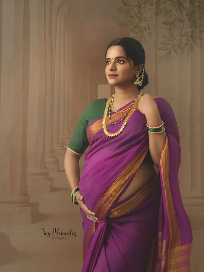 A classic pose against a fine art backdrop, this portrait in a purple saree has the timeless quality of a traditional Indian painting.