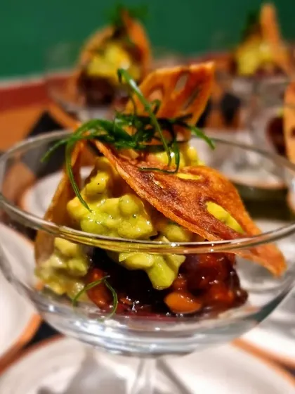 An Asian-inspired avocado and water chestnut tartare served in a glass. The crispy lotus root chip adds a wonderful textural contrast.