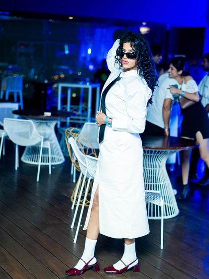 A guest poses in a stylish white outfit, embodying the theme of the party. I create an environment where fashion and music intersect, making it a place to see and be seen.