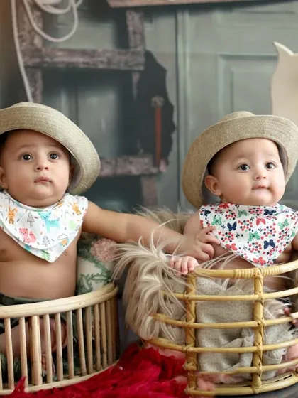 Double the trouble, double the fun. These six-month-old twin cowboys look adorable in their matching hats and bibs, sitting in rustic baskets as part of a western-themed milestone session.