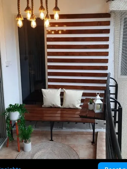 A full view of this cozy and modern balcony. The custom pinewood bench is paired with matching wall slats and beautiful rope lighting for a complete look.