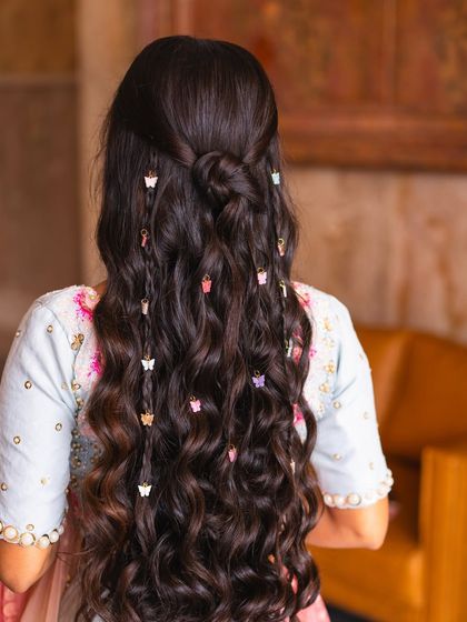 A playful and trendy hairstyle featuring soft waves and cute butterfly clips. This is a great option for a Mehendi or Haldi ceremony, adding a touch of fun and personality to the look.