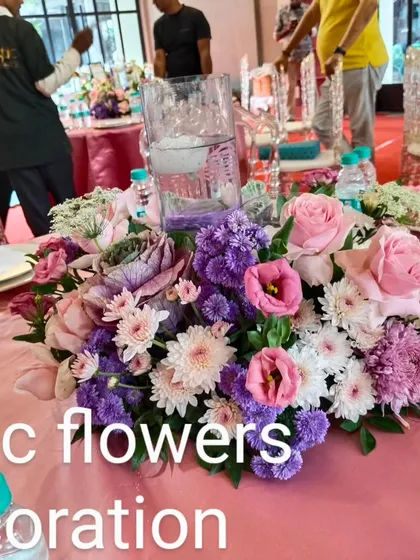 A beautiful floral centerpiece for a party table. This arrangement features a mix of pink roses and purple and white chrysanthemums, adding a touch of elegance to the event.