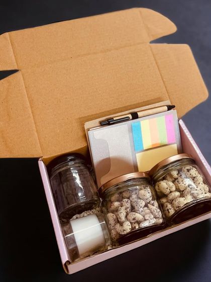 This budget-friendly corporate gift box includes three jars for nuts or snacks, a notebook with a pen, and a candle, offering great utility and a personal touch.