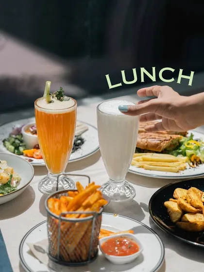 A hand reaching for a cool milkshake during a delicious lunch. It’s the perfect way to balance a savory meal.