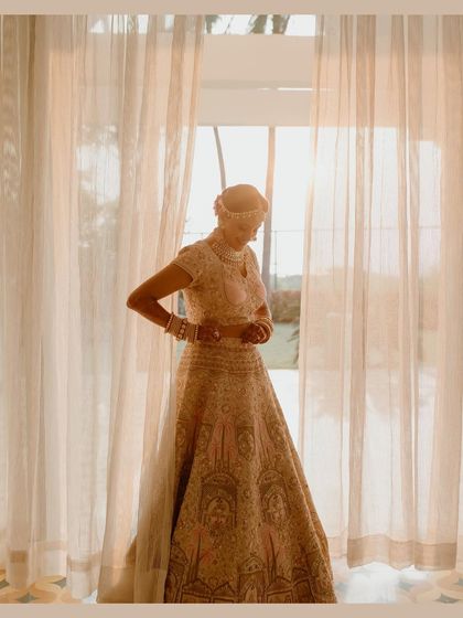 A beautifully lit portrait of the bride getting ready by a window. The soft, natural light filtering through the sheer curtains creates a serene and timeless feel.