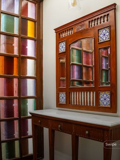 This unique entryway features a console table and a decorative mirror set against a wall of colorful stained glass. It’s a playful and artistic touch that makes a memorable first impression.