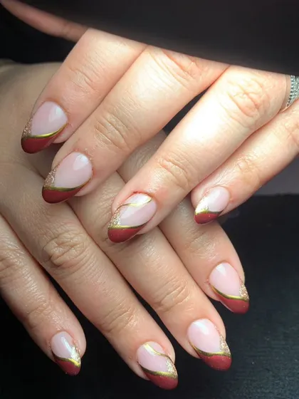 A classic and elegant French manicure with a twist. This design features deep red tips with a delicate gold line separating the color from the nude base.
