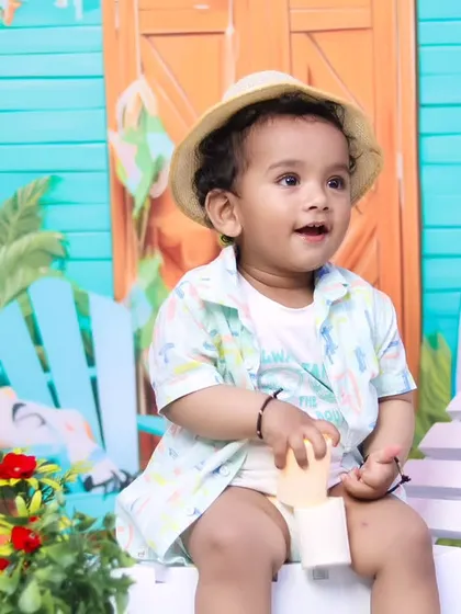 A stylish toddler in a hat and casual shirt enjoys the beach-themed set. We provide costumes and props for all our themes.