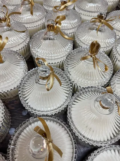 A close-up of our elegant crystal jar candles, prepared as wedding favors. These jars are a popular choice for their timeless design and can be filled with a fragrance of your choice. They make for a beautiful and reusable gift that guests will appreciate long after the event.