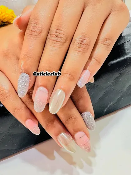 A neutral yet glamorous set featuring a mix of pink, nude, and silver glitter nails in different textures.