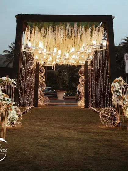 A closer look at the details. This entrance combines hanging chandeliers, cascading white flowers, and thousands of fairy lights to create a dense, sparkling canopy that feels utterly magical.