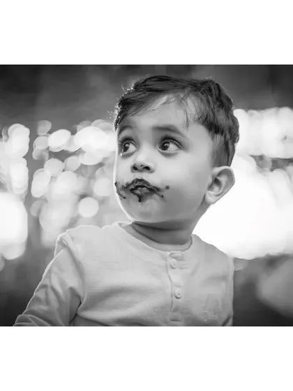 The beautiful bokeh in the background is enhanced in this black and white portrait of Ivaan. His upward glance and chocolate-smudged face create a captivating and artistic image.