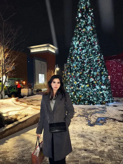 A full-length shot of my winter outfit against the festive Christmas tree lights.