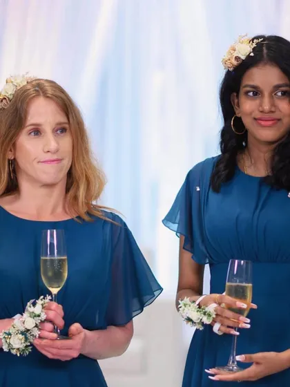 Two bridesmaids sharing a moment during the reception. They are wearing the custom white floral hair clips and wrist corsages I made to complement their dresses.