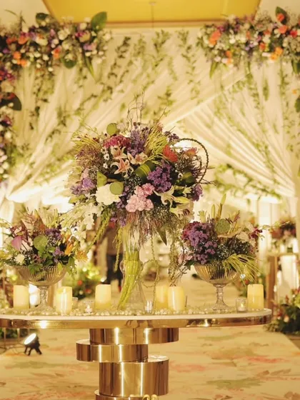 A grand floral tablescape set against a beautifully draped backdrop. This setup combines lush flowers and candlelight to create a luxurious focal point for the celebration.