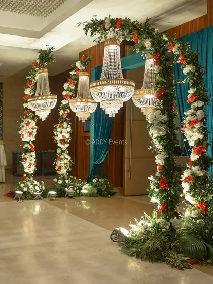 We believe in making a grand statement from the moment guests arrive. This opulent entrance features lush floral arches intertwined with magnificent crystal chandeliers, setting a tone of romance and luxury for an indoor wedding event.