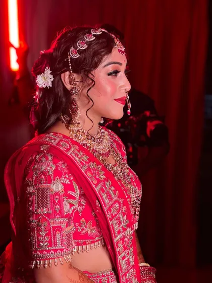 A side profile of the bride in her classic red Sabyasachi lehenga. The makeup is regal and timeless, with a focus on creating an ethereal glow.
