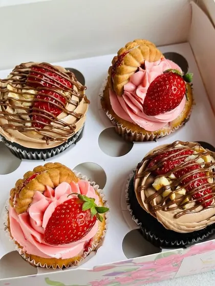 This assortment box showcases my fruit-inspired gourmet cupcakes. It includes my Jimjam strawberry cupcake with a biscuit topping and fresh strawberry, alongside a Nutella strawberry cupcake drizzled with chocolate. It's a perfect blend of fruity and decadent flavors.