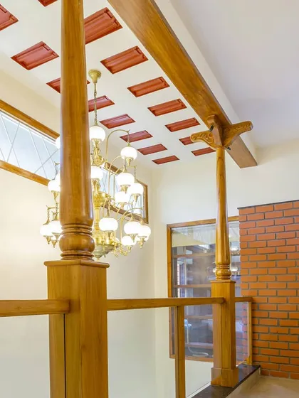 In this contemporary Indian home, I used traditional wooden columns and a filler slab ceiling to create a sense of heritage and volume. The grand chandelier adds a touch of elegance to the double-height space.