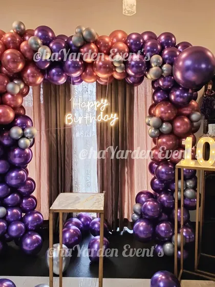 A metallic balloon arch with a 'Happy Birthday' neon sign and a light-up number '10'.