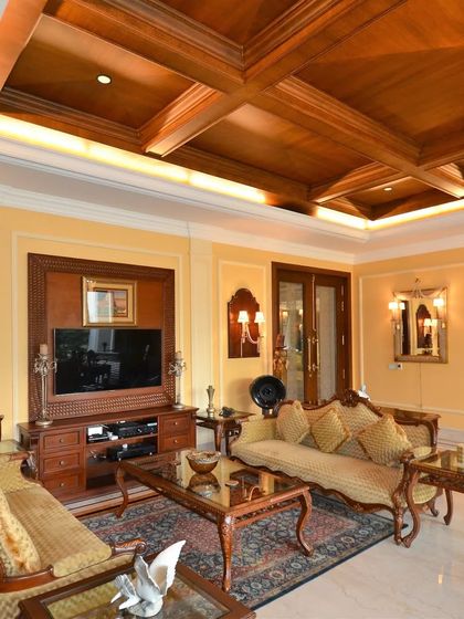 This living room is a masterpiece of intricate details, from specialized moldings to handcrafted wooden furniture. The space exudes a royal ambiance with its classical architectural elements and rich textures.