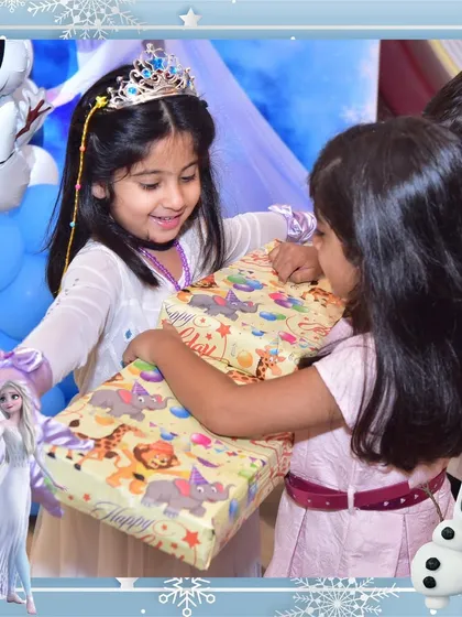 A heartwarming moment of friendship at a Frozen-themed party. The birthday princess receives a gift from her friend, a perfect example of the special bonds celebrated here.