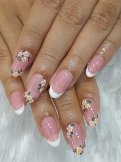 A delicate and feminine French manicure with a twist. This look combines the classic white tip with accent nails featuring tiny, hand-painted daisies for a fresh, springtime feel.