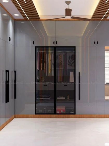 A view of the L-shaped glass wardrobe in the grey bedroom, which also includes a window seat and open shelving.