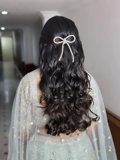 Adding a touch of elegance with a simple, sparkling bow. This half-up, half-down hairstyle with soft curls is romantic and chic.