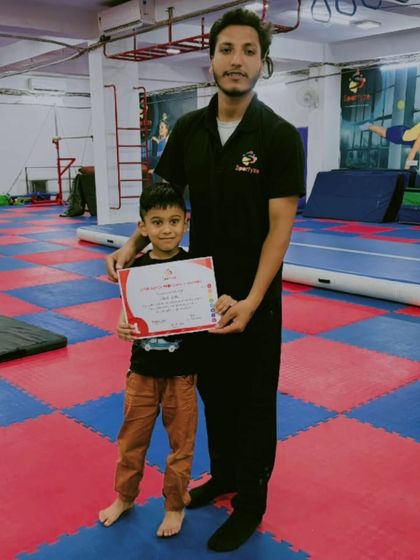 This young boy looks proud to receive his certificate of achievement, marking another step forward in his gymnastics training.