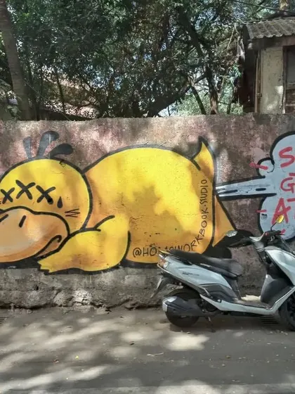 A humorous piece of graffiti in Bandra featuring a knocked-out yellow duck. The speech bubble "Sorry to grab your attention" adds a layer of wit to the cartoonish art.