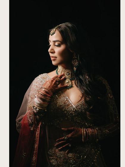 A classic, moody portrait of bride Chitranksha. The dark background makes her and her intricate jewelry stand out, creating a dramatic and captivating image.