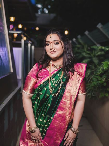 The bride looking stunning in a green and pink saree for her engagement. The makeup is glamorous yet traditional, suitable for an evening event.