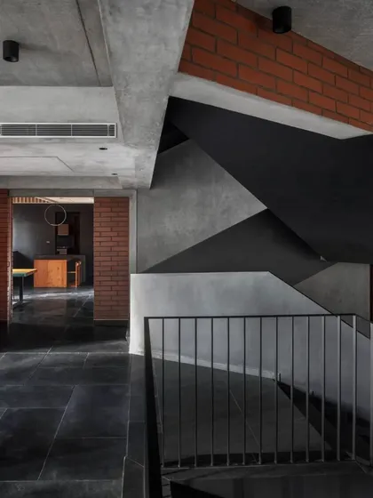 A view from the upper landing of the Brick House, looking down at the complex geometry of the staircase as it unfolds through the central volume of the home.