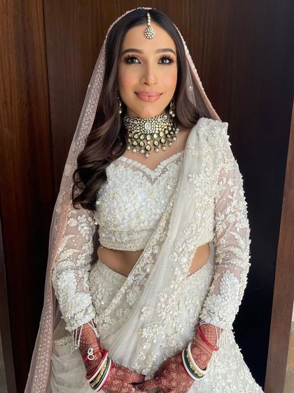 A happy bride showing off her complete look, with her hair styled in simple yet elegant waves.