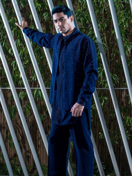 This navy blue layered ensemble features a subtly textured jacket over a matching kurta. The monochromatic look is both modern and elegant, suitable for a variety of formal and semi-formal events.