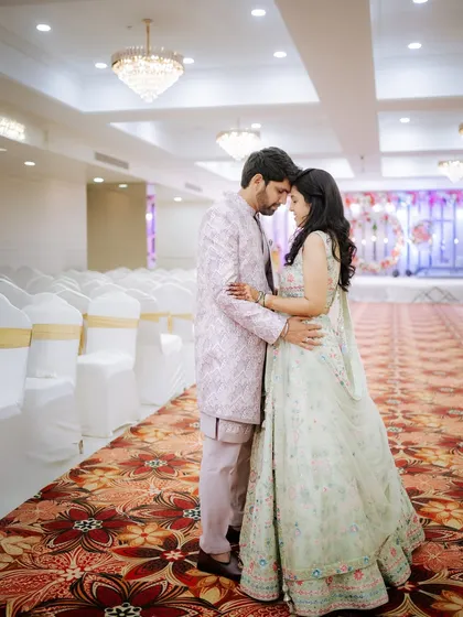 A quiet moment before the guests arrive. This wide shot captures the couple in an intimate pose within the grand, empty banquet hall, creating a sense of peace and anticipation before their engagement party.