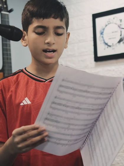 A young student carefully reads his sheet music while practicing at the microphone. We teach sight singing and music reading in our vocal classes.