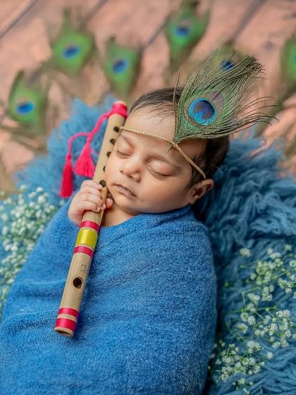 A sweet portrait of the baby holding the flute, a classic element of Lord Krishna imagery.