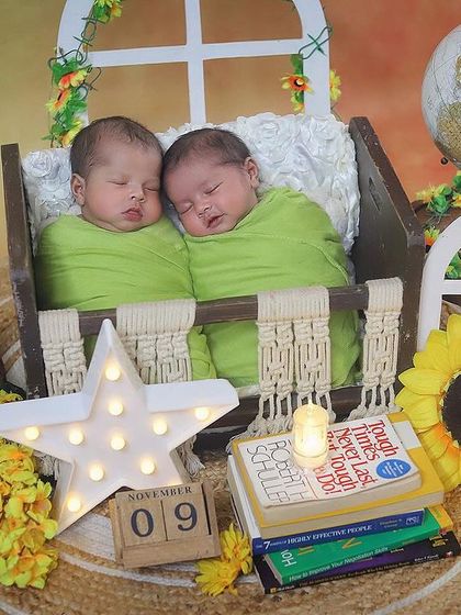 These twin boys are ready to take on the world together. This creative setup includes a globe, books, and sunflowers, creating a fun and adventurous theme for their newborn portraits.