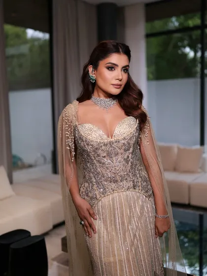 A wider shot showing the magnificent Tarun Tahiliani gown in a modern, luxurious setting. The makeup is bold and glamorous, designed to match the drama of the outfit.
