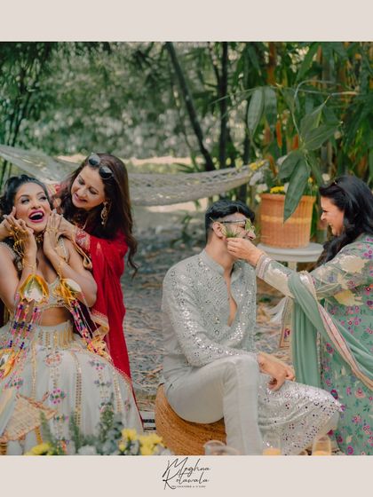 Playful moments with the family. The bride's mother and mother-in-law-to-be share a fun moment with the groom, all styled in outfits that reflect their personal style while fitting the event's theme.