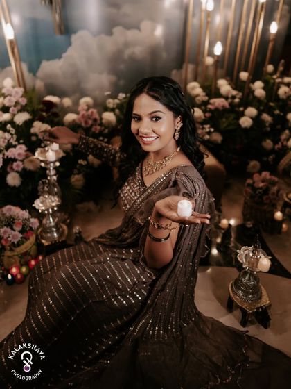 The bride smiling as she holds small candles, part of her beautiful Mehendi ceremony setup.