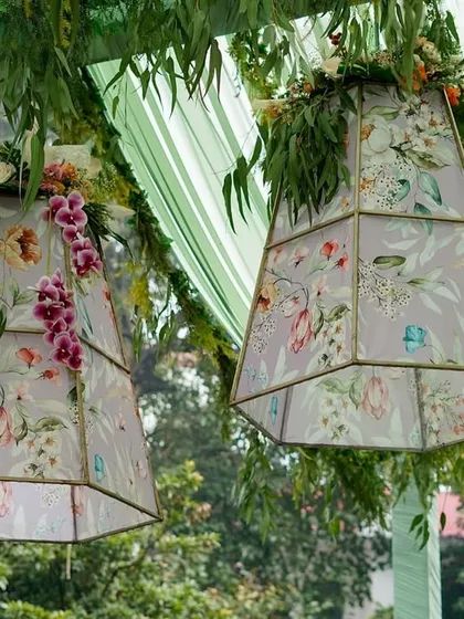 A close-up of the beautiful hanging lampshades, adorned with fresh orchids and greenery.
