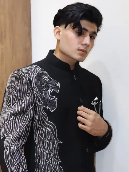 A confident pose in the custom lion-embroidered Jodhpuri. This jacket is a testament to our ability to create unique, high-fashion pieces that command attention.