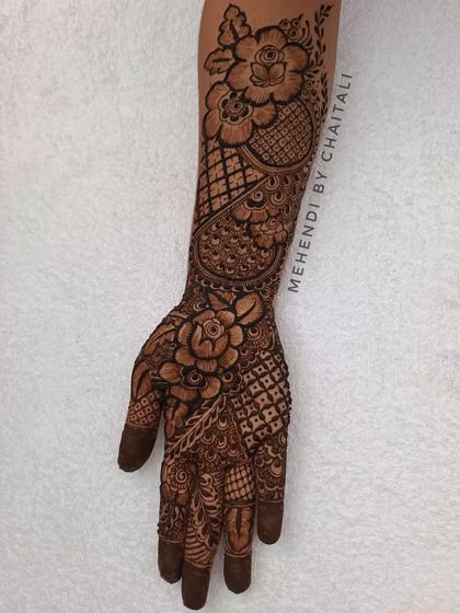 This design is a beautiful mix of floral and traditional styles. The large, shaded roses on the hand and arm are combined with classic geometric patterns for a unique look.