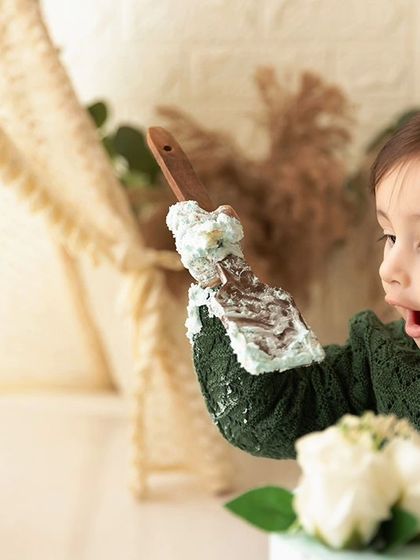 A moment of discovery, as he examines the frosting on a spoon during his cake smash session.