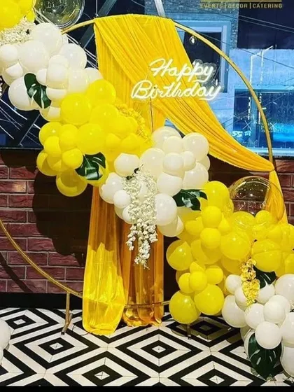 A bright and sunny birthday setup with a yellow and white balloon arch on a gold ring, perfect for a cheerful celebration.
